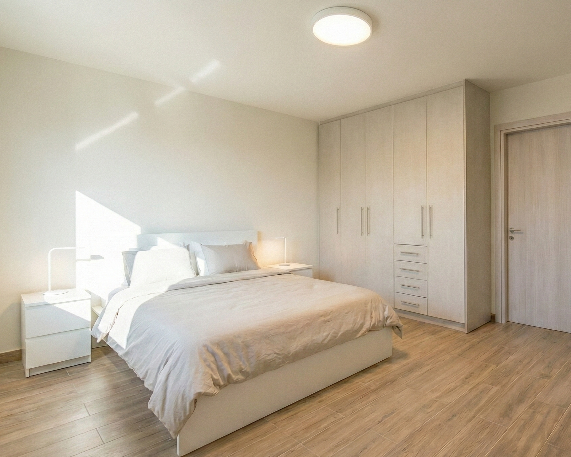 Φωτεινό master υπνοδωμάτιο με διπλό κρεβάτι, μεγάλη ανοιχτόχρωμη εντοιχισμένη ντουλάπα, τύπου ξύλο δάπεδο και φυσικό φως που μπαίνει από αριστερά.